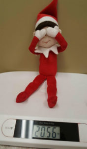 Eddie the Elf covering his eyes and sitting on a weighing scale